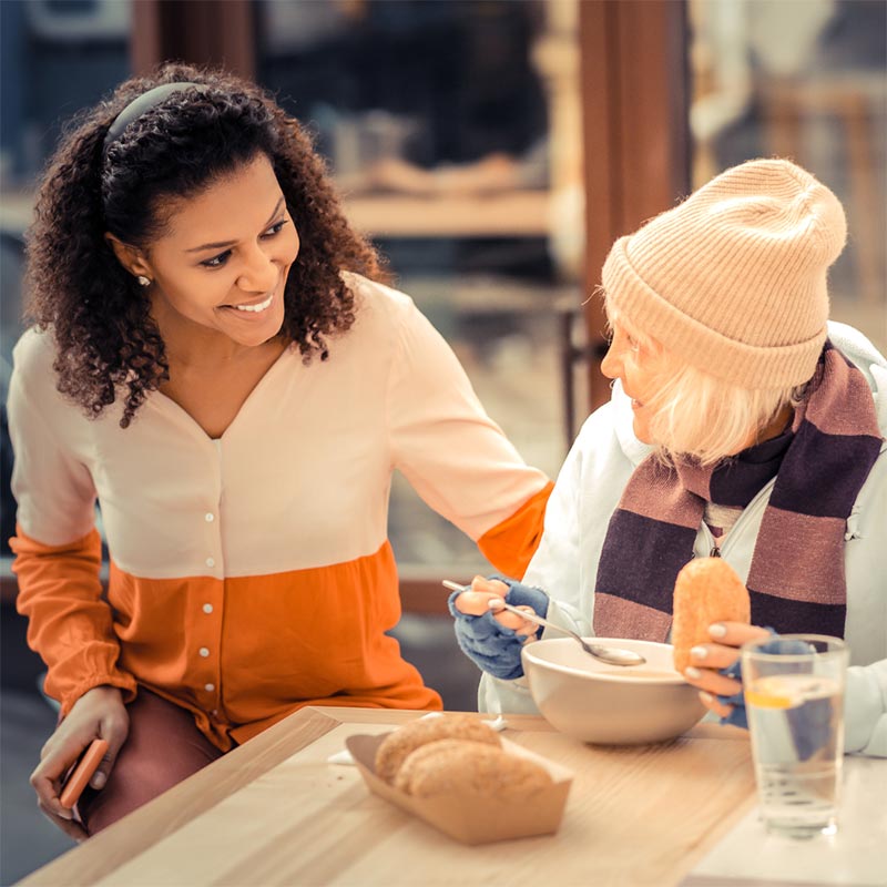 A lady talking to an elderly lady who appears to be homeless.