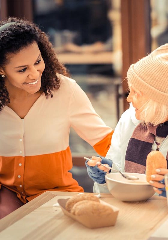 A lady talking to an elderly lady who appears to be homeless.